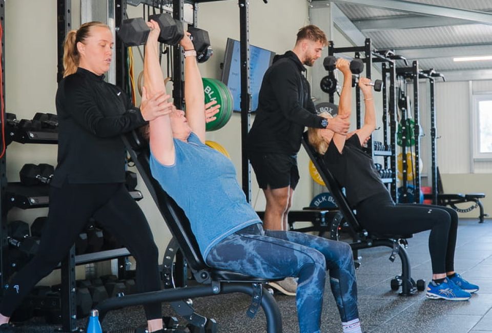 Two people working out with a personal trainer