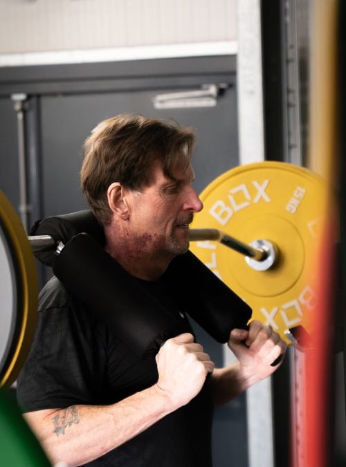 Man exercises in squat rack